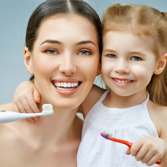 Smiling mother and daughter with toothbrushes.
