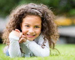Smiling child lying on grass outdoors.