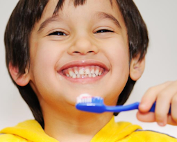Smiling child holding a blue toothbrush